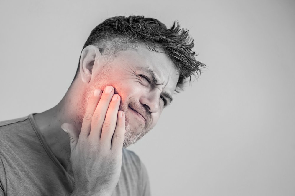 Patient holding their jaw in dental pain before an emergency visit