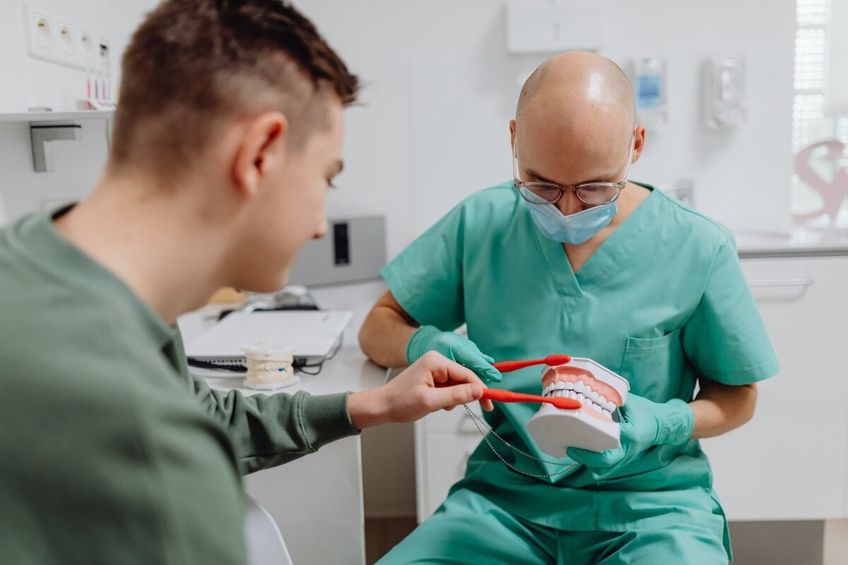 Dentist showing a patient a model of a dental bridge during a consultation